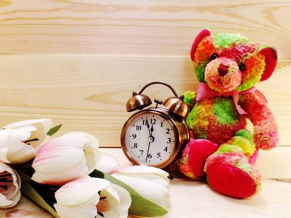 Tedy dragen met wekker en boeket bloemen op houten achtergrond — Stockfoto