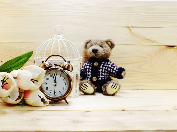 Плюшевый мишка с будильником и букет цветов на деревянном фоне — стоковое фото