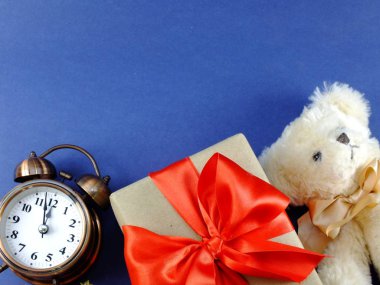 çalar saat ve üzerinde mavi arka plan izole şerit yay ile geri dönüşümlü kağıt sarılmış hediye kutusu