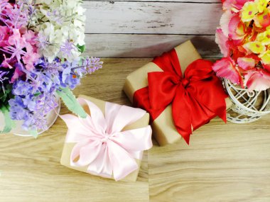 Şerit üzerinde ahşap arka plan güzel çiçekler buket ve hediye kutusu