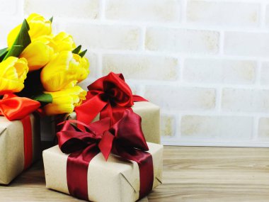 Şerit üzerinde ahşap arka plan güzel çiçekler buket ve hediye kutusu