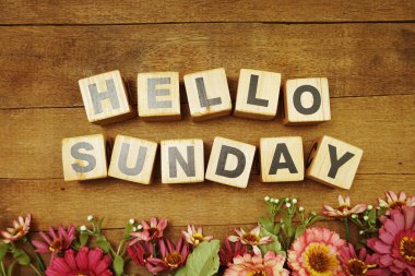 Merhaba, ahşap arka planda çiçek buketi olan Pazar alfabesi harfi.