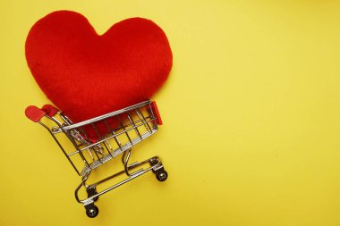 Sarı arka plan üzerinde Kırmızı Kalp ve Mini Trolley Alışveriş Sepeti