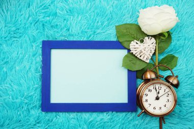 Düz uzayda yatıyordu. Çalar saat ve şakayık çiçekli fotoğraf çerçevesi.