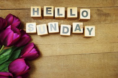 Merhaba, ahşap arka planda lale çiçeği buketi olan Pazar alfabesi harfleri.