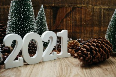 Yeni yılınız kutlu olsun. Ahşap zemin üzerinde Noel ağacı ve çam kozalağı süslemesi olan şenlikli bir geçmiş.