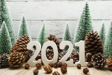 Yeni yılınız kutlu olsun. Ahşap zemin üzerinde Noel ağacı ve çam kozalağı süslemesi olan şenlikli bir geçmiş.