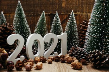 Yeni yılınız kutlu olsun. Ahşap zemin üzerinde Noel ağacı ve çam kozalağı süslemesi olan şenlikli bir geçmiş.