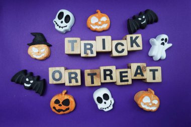 Cadılar Bayramı konsepti düz yatıyordu mor arkaplan üzerinde şaka mı şeker mi alfabesi harfleri