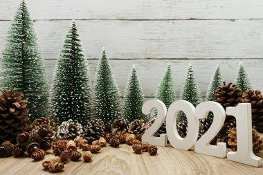Yeni yılınız kutlu olsun. Ahşap zemin üzerinde Noel ağacı ve çam kozalağı süslemesi olan şenlikli bir geçmiş.