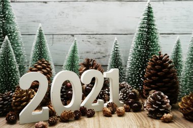 Yeni yılınız kutlu olsun. Ahşap zemin üzerinde Noel ağacı ve çam kozalağı süslemesi olan şenlikli bir geçmiş.