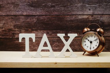 Ahşap zemin üzerinde alarm saati ve Vergi alfabesi harfi