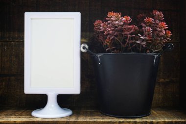 Boş ekran çerçeve standı ve ahşap arka planda yapay bitki ev dekorasyonu