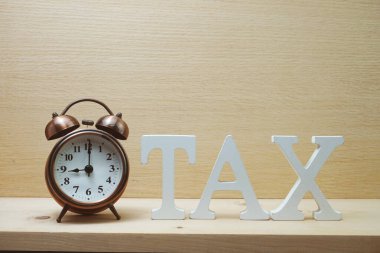 Tahta arka planda vergi konsepti vergi alfabesi harfleri ve alarm saati ödeme zamanı