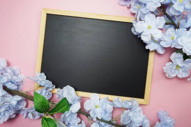 Pembe arka planda uzay siyah tahtası ve çiçek buketi dekorasyonu