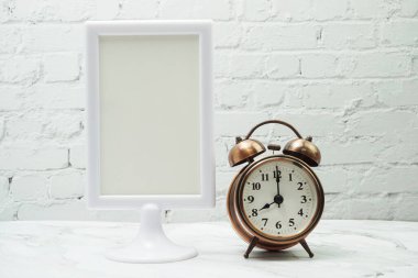 Boş çerçeve standını ve alarm saatini tahta arkaplanda göster.