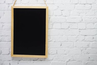 Beyaz tuğla duvar arka planında boş siyah tahta