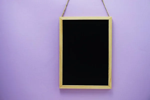 紫色の壁のテクスチャの背景に空の黒いボード — ストック写真