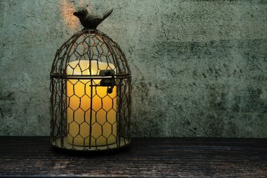 Kuş kafesi ve mum ışığı grunge concreat ve ahşap arka planda