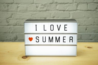 Yaz kelimelerini beyaz tuğla duvardaki ışık kutusunda ve tahta arka planda seviyorum.