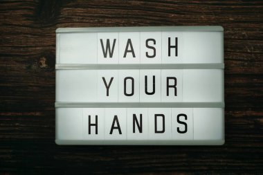 Ellerinizi yıkayın sözcüğü tahta arka planda ışık kutusunda üstten görünün