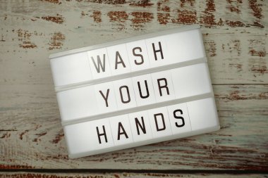 Ellerinizi yıkayın sözcüğü tahta arka planda ışık kutusunda üstten görünün