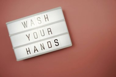 Düz bir şekilde uzanıp, pembe arka planda pembeyle parlayan ışık kutusunda ellerinizi yıkayın.