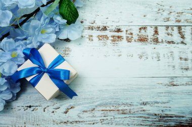Mavi Hediye Kutusu ve çiçek süslemesi ahşap arka planda