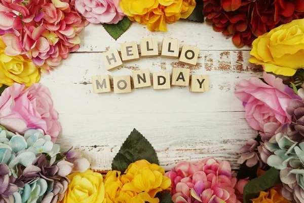 Hello Monday alphabet letter with colorful flowers border frame on wooden background