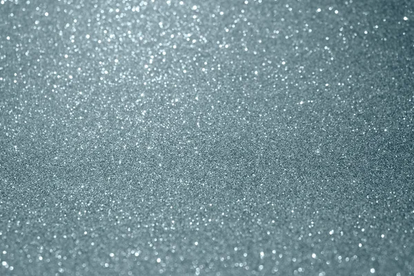 Zilver glitter en sprankelende vervagen bokeh licht effect op sneeuw witte achtergrond. Glinsterende zilver of lichtend deeltjes structuur met fonkelende licht voor moderne Kerstmis achtergrond ontwerpsjabloon — Stockfoto