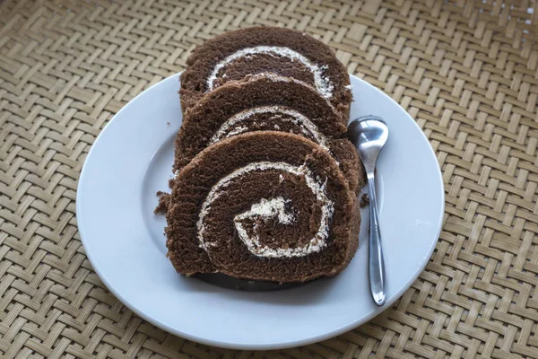 Pastel de rollo de chocolate con crema en un plato — Foto de Stock