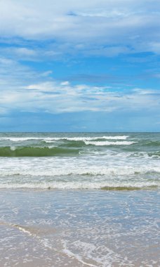 Okyanus dalgaları ve mavi gökyüzü bulutlu