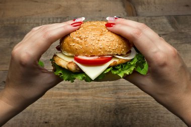 Hamburger yeme. Lezzetli hamburger elinde. Fastfood yemek.