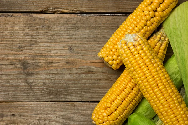 Ripe yellow sweet corn cob on a wooden table. Top view. — Stock Photo, Image
