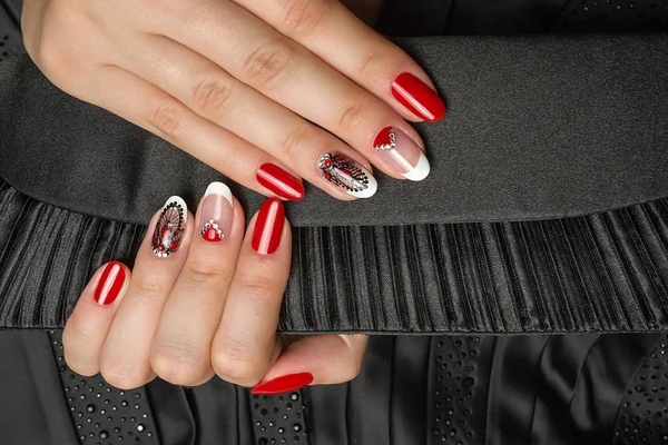 Franse manicure - mooie verzorgde vrouw handen met rode en zwarte manicure met strass op zwarte achtergrond — Stockfoto