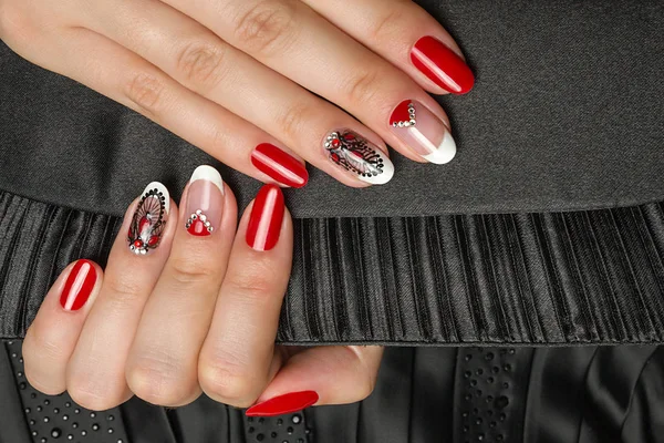 Manicure francês - belas mãos femininas cuidadas com manicure preto e branco vermelho com strass no fundo preto Imagem De Stock