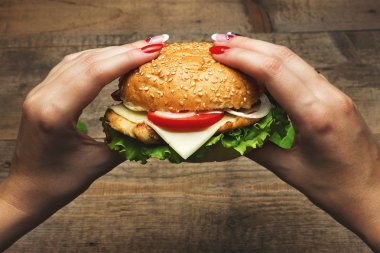 Hamburger yeme. Lezzetli hamburger elinde. Fastfood yemek. Tonda vintage