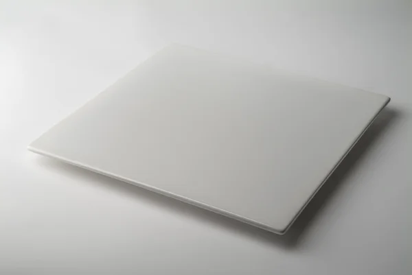 Єдина квадратна біла тарілка на білому столі — стокове фото