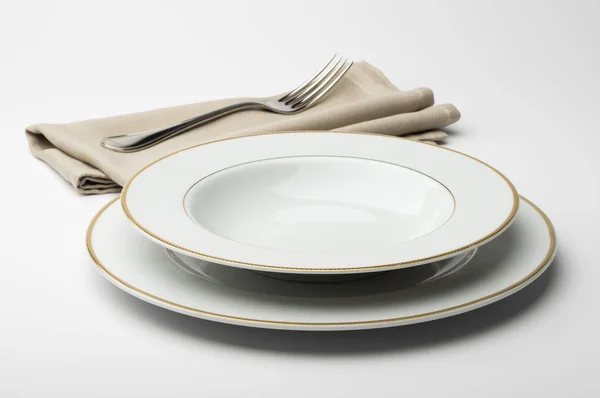 Пустая круглая белая тарелка и миска с салфеткой и вилкой — стоковое фото