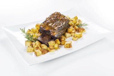 Dikdörtgen beyaz tabak pişmiş biftek kaburga ve kavrulmuş patates ile