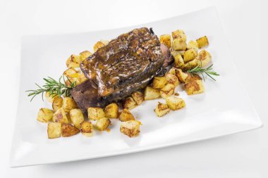 Dikdörtgen beyaz tabak pişmiş biftek kaburga ve kavrulmuş patates ile