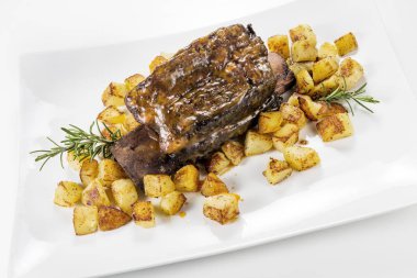 Dikdörtgen beyaz tabak pişmiş biftek kaburga ve kavrulmuş patates ile