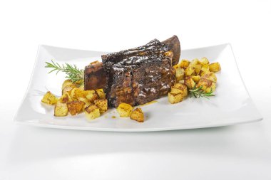 Dikdörtgen beyaz tabak pişmiş biftek kaburga ve kavrulmuş patates ile