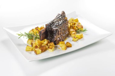 Dikdörtgen beyaz tabak pişmiş biftek kaburga ve kavrulmuş patates ile