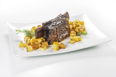 Dikdörtgen beyaz tabak pişmiş biftek kaburga ve kavrulmuş patates ile