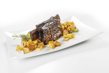 Dikdörtgen beyaz tabak pişmiş biftek kaburga ve kavrulmuş patates ile
