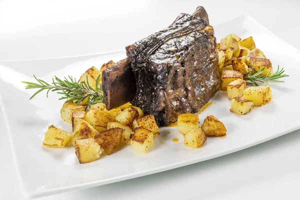 Dikdörtgen beyaz tabak pişmiş biftek kaburga ve kavrulmuş patates ile