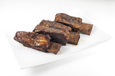 Üç pişmiş dana kaburga ile beyaz dikdörtgen plaka