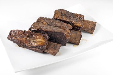 Üç pişmiş dana kaburga ile beyaz dikdörtgen plaka