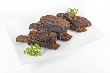 Üç pişmiş dana kaburga ile beyaz dikdörtgen plaka